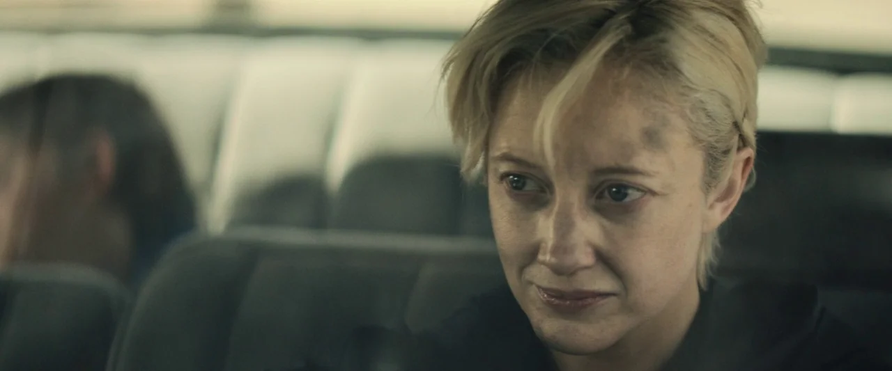 The Grudge (2020) movie still: closeup — A woman sits inside a car during the day. She is looking out a window with a smudge of dirt on her face.