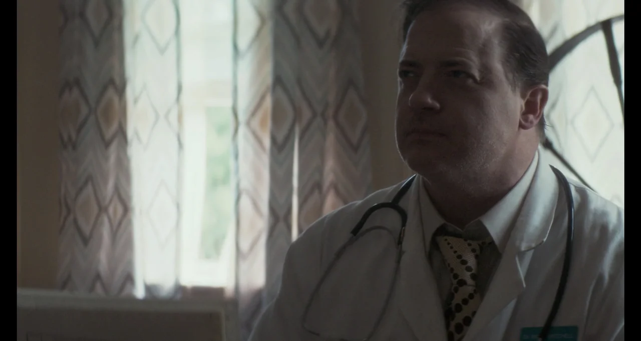 The Poison Rose (2019) movie still: medium — A medical office features a window with patterned curtains in the background. A doctor wears a white…