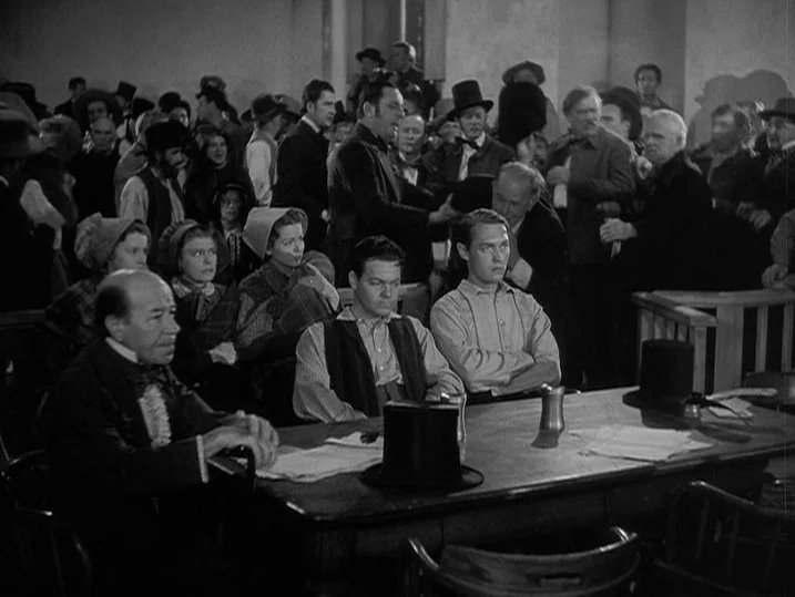 Young Mr. Lincoln (1939) movie still: medium — A crowded 19th-century courtroom with rows of wooden benches packed with spectators. Men and women…