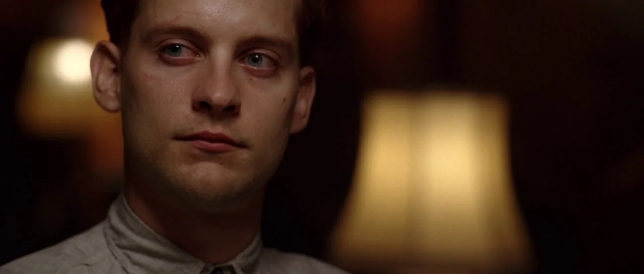 Seabiscuit (2003) movie still: closeup — A dimly lit room features a blurred lamp in the background. A young man looks towards the side of the frame.