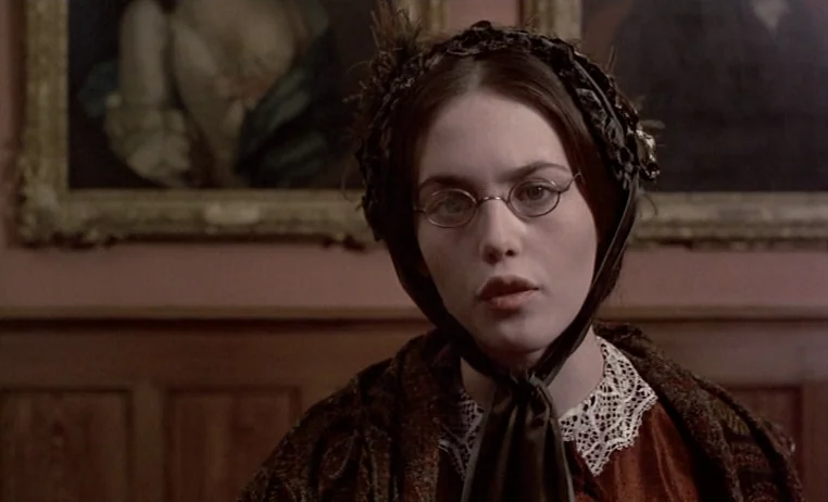The Story of Adele H (1975) movie still: closeup — An interior gallery space with dark wood paneling and framed oil paintings behind a woman. The…