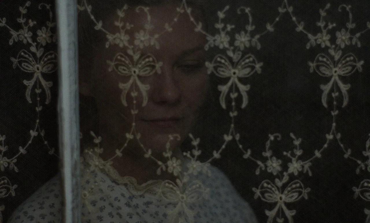 The Beguiled (2017) (2017) movie still: closeup — A dark interior room features a fine-mesh lace curtain with floral and bow patterns. A woman…