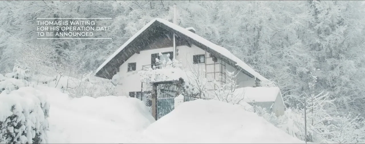 Hunting for Hedonia (2019) movie still: establishing — A white chalet-style house is surrounded by a dense forest covered in heavy snow. The…