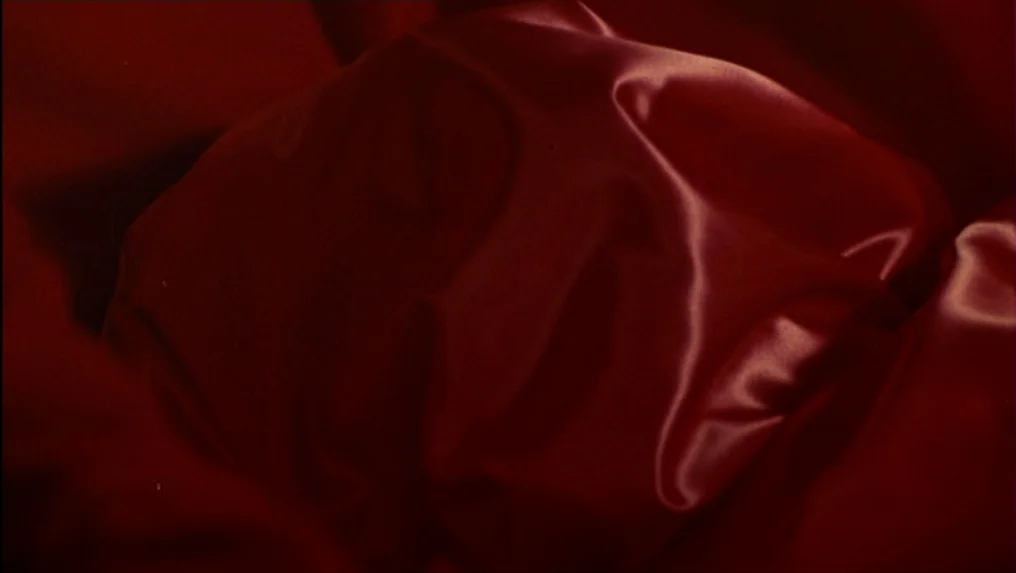 Targets (1968) movie still: closeup — A close-up view shows a mass of bunched red silk or satin fabric. Deep folds and shadows define the texture…