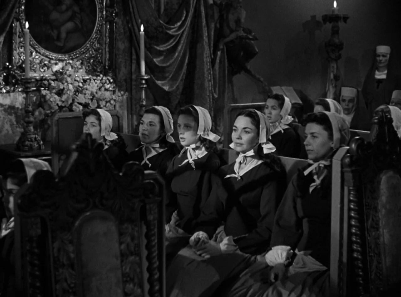 Madame Bovary (1949) movie still: medium — A dark church interior features multiple women in bonnets sitting in wooden pews. The women sit in a row…
