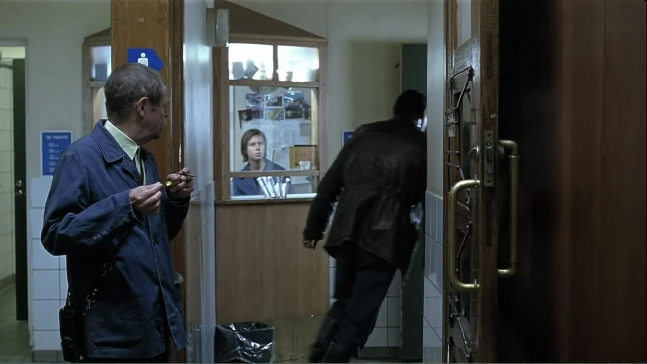 The Man Without a Past (2002) movie still: medium — A utilitarian lobby space with tiled walls and wooden door frames features an information…