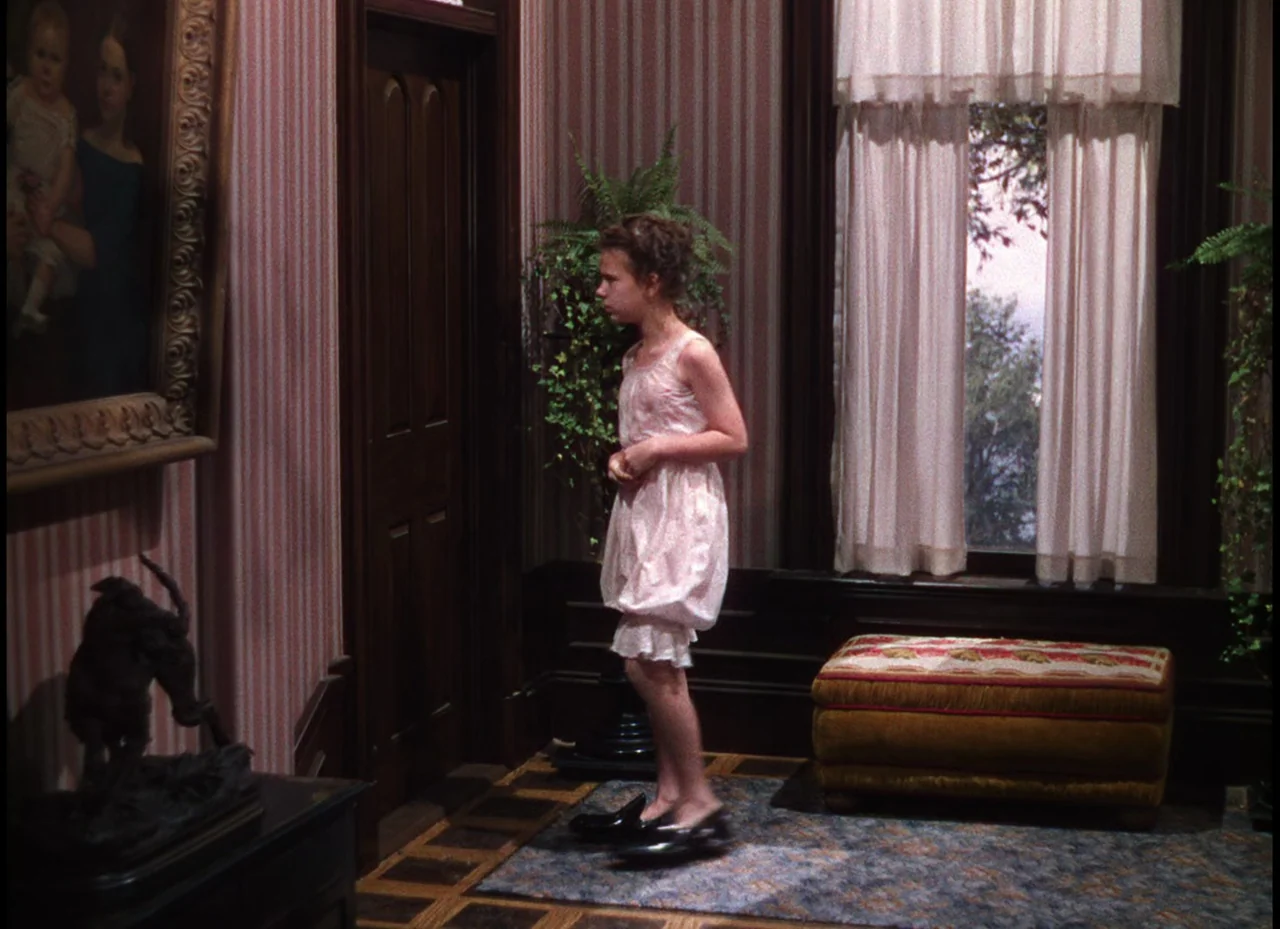 Meet Me In St. Louis (1944) movie still: fullbody — An interior hallway features striped wallpaper, dark wood trim, and an ornate painting. A young…