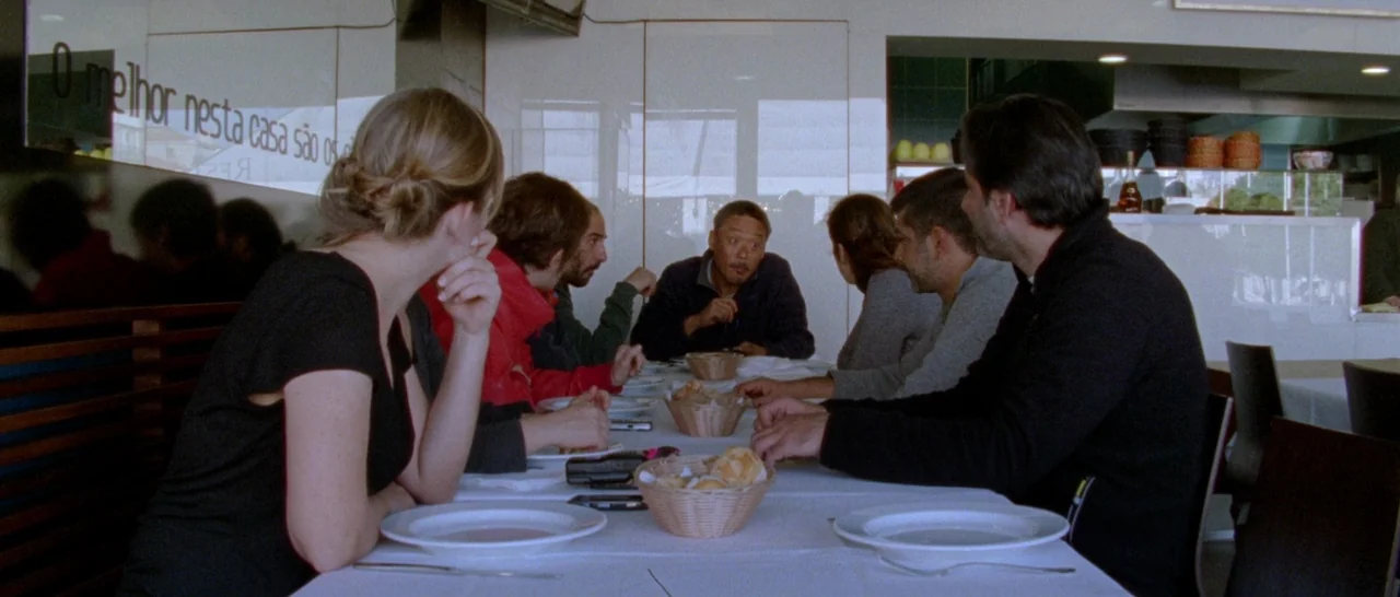 Arabian Nights: Volume 1 – The Restless One (2015) movie still: medium — A group of people are seated at a long white-clothed table in a restaurant.…