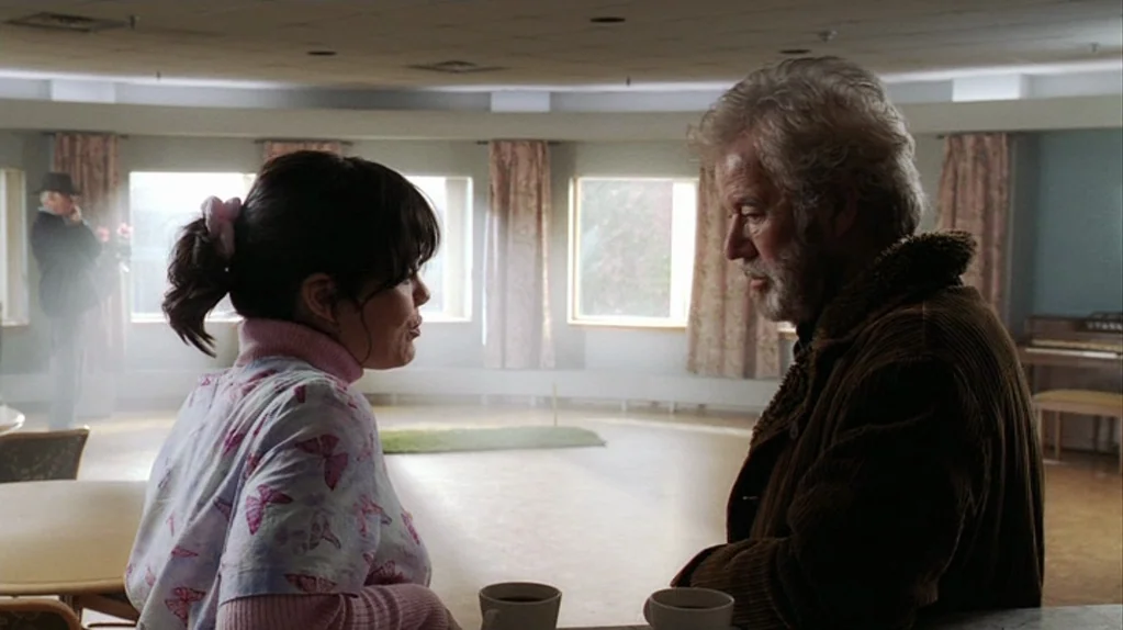 Away From Her (2006) movie still: medium — A spacious, brightly lit community hall features large windows and simple interior furnishings. A woman…