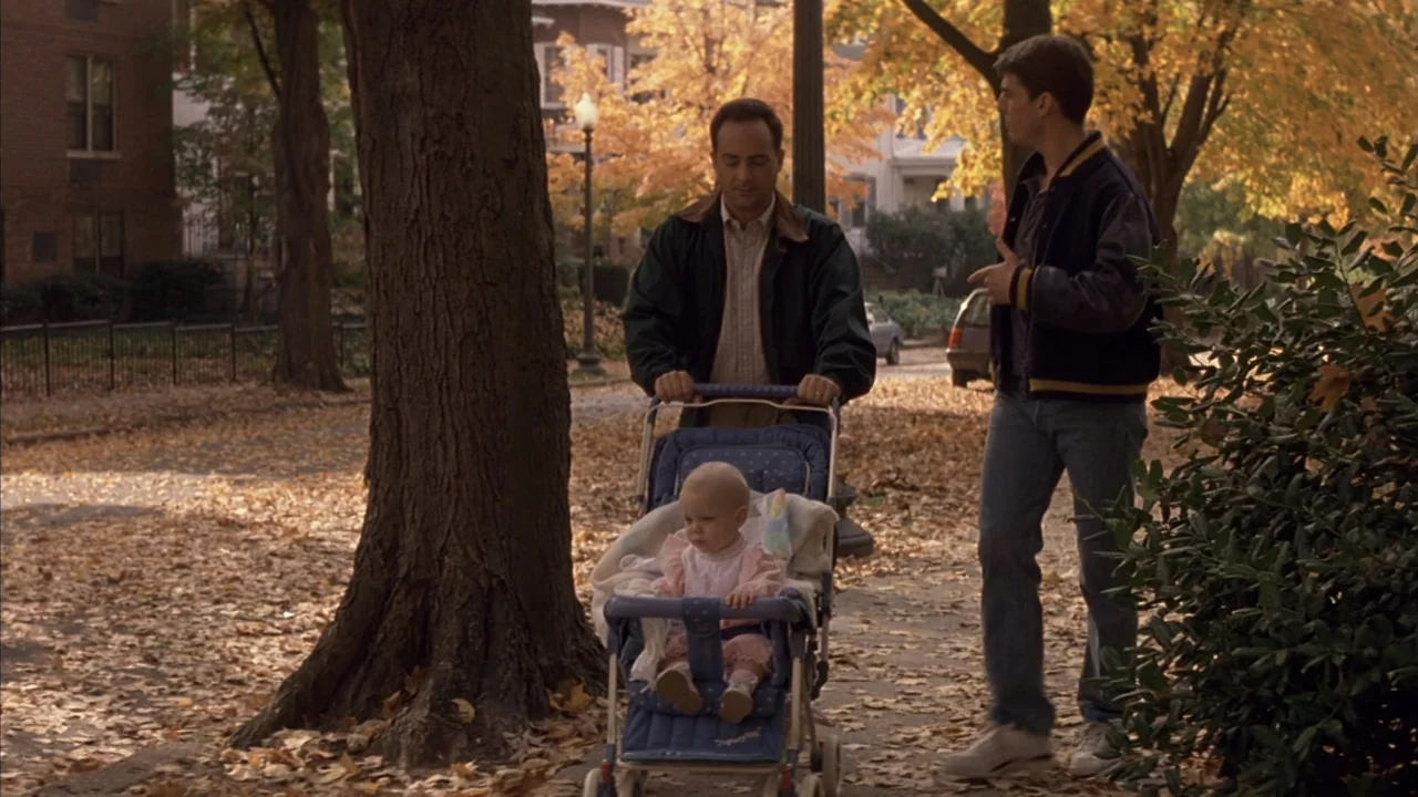 A Few Good Men (1992) movie still: fullbody — A leaf-covered suburban sidewalk lined with large trees during the autumn season. A man pushes a…