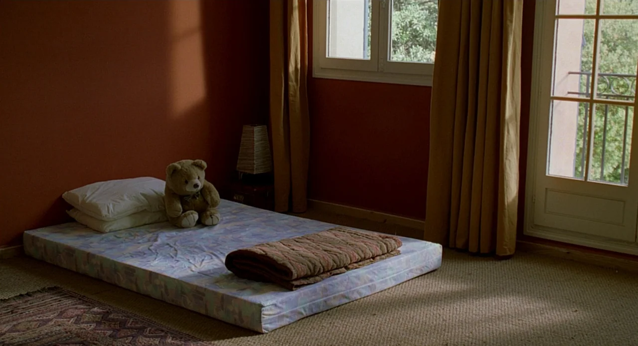 Swimming Pool (2003) movie still: wide — A sparsely furnished room features terracotta-colored walls and a mattress placed on the floor. A single…