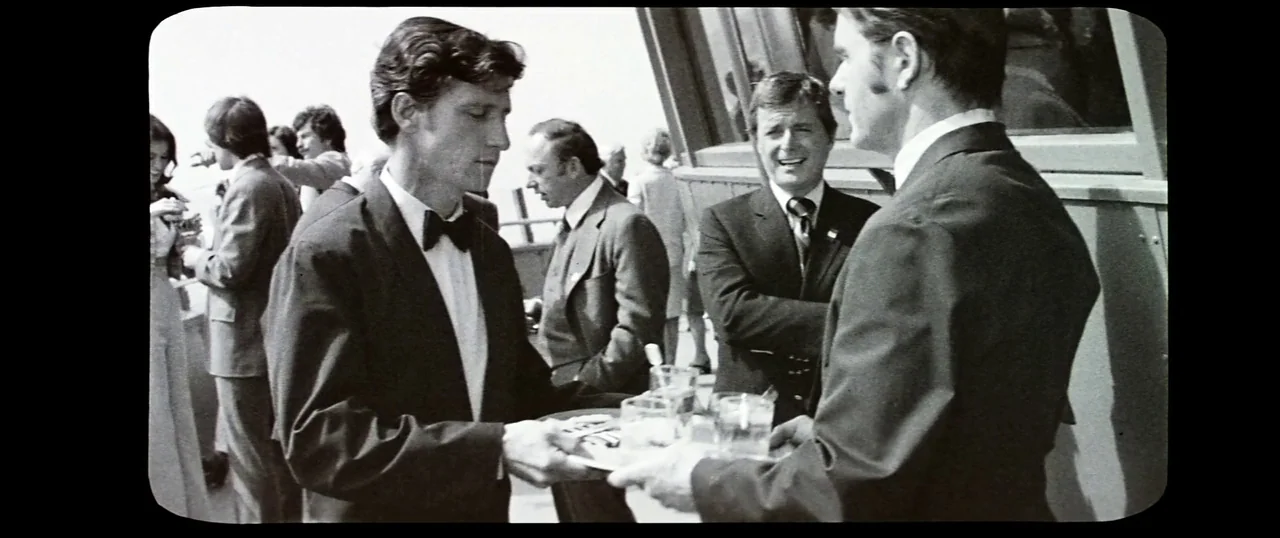 The Parallax View (1974) movie still: medium — An outdoor gathering on a terrace with several people in formal business attire. A waiter in a tuxedo…
