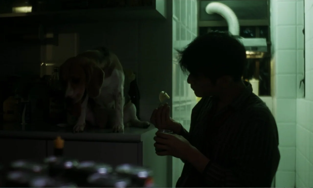 Chungking Express (1994) movie still: medium — A small kitchen interior features tiled walls and a low-lit cooking area at night. A young man sits…