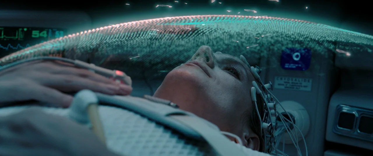 Oxygen (2021) movie still: closeup — A high-tech medical pod interior features a reclining patient connected to diagnostic machinery. The woman…