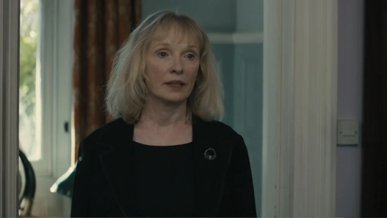About Time (2013) movie still: medium — A residential interior corridor with light blue walls and a white doorway frame. An older woman with blonde…