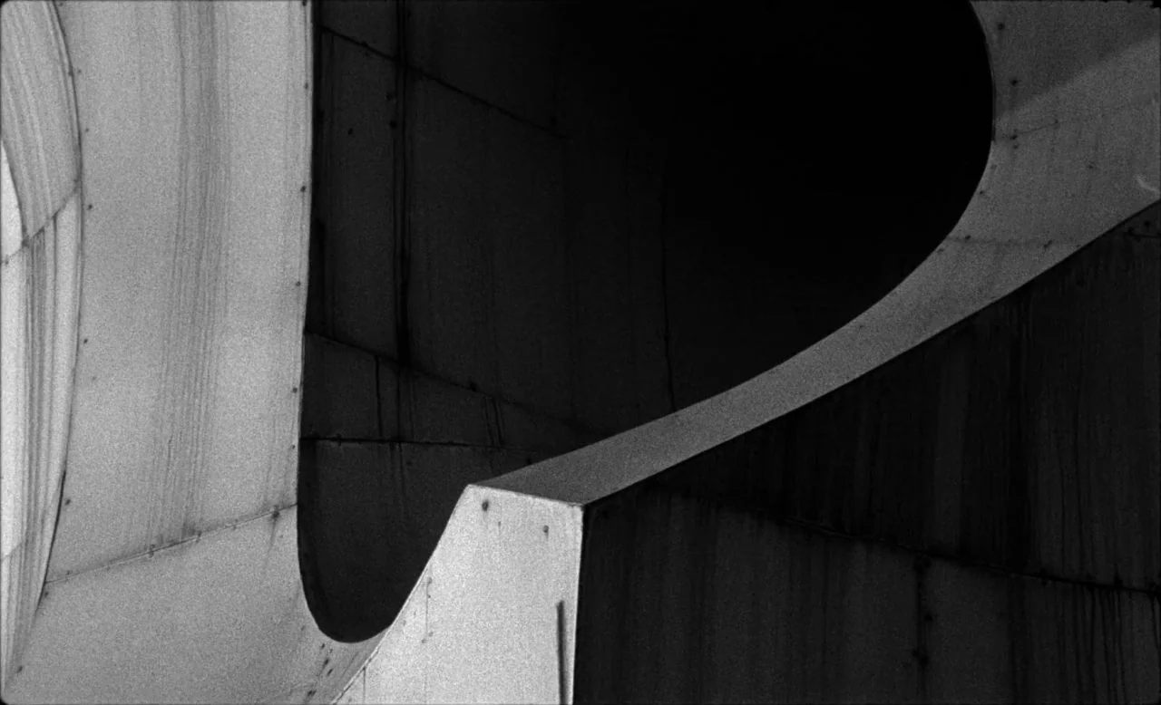Last and First Men (2020) movie still: establishing — A close-up view of weathered concrete architectural forms with smooth, intersecting curved…
