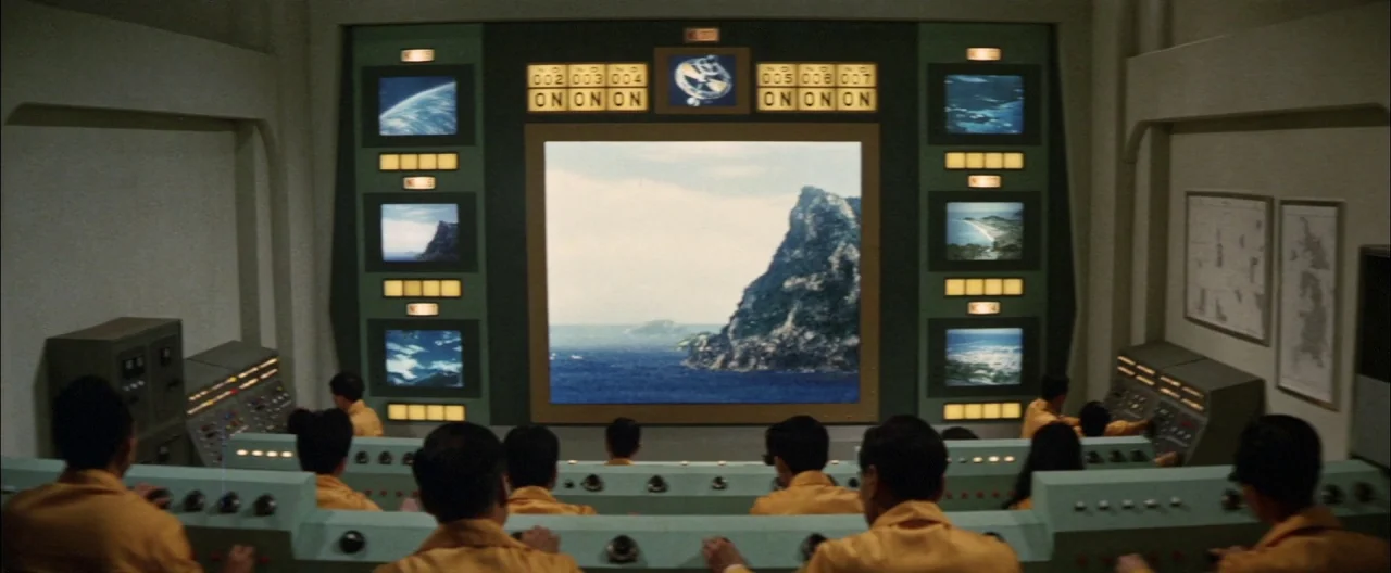 Destroy All Monsters (1968) movie still: wide — A 1960s science fiction command room features a large central screen flanked by monitors. Multiple…