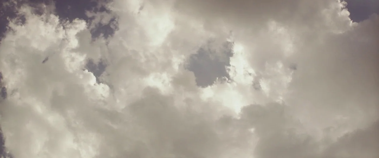 God’s Pocket (2014) movie still: establishing — An expanse of thick, layered clouds fills the entire frame. Natural light creates varying shades of…