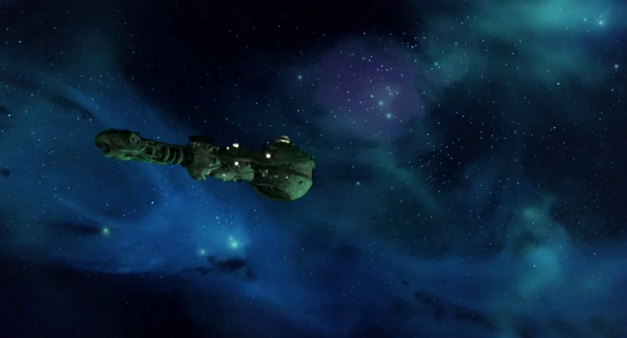 Explorers (1985) movie still: wide — A dark, expansive void of outer space filled with blue and purple nebula clouds. A large green mechanical…