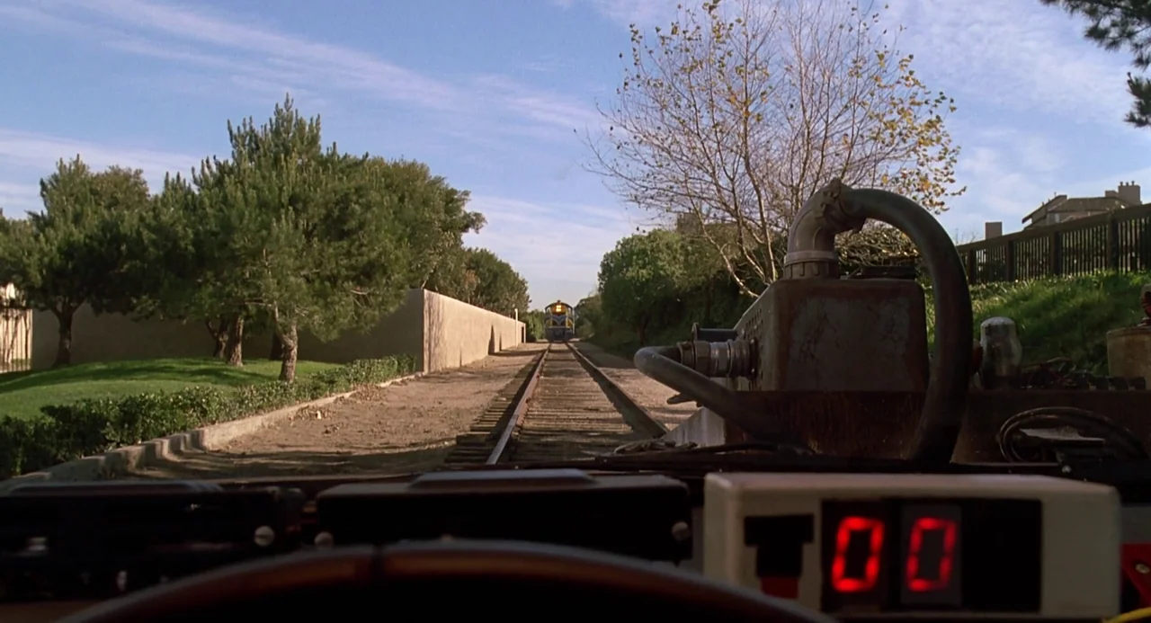 Back To The Future Part III (1990) movie still: wide — A rural railway track stretches toward a train approaching in the far distance. A piece of…
