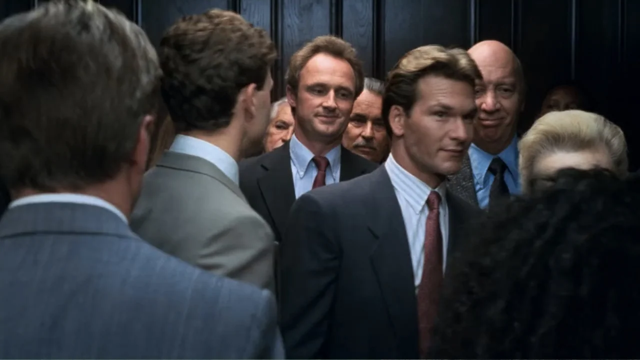 Ghost (1990) movie still: medium — A crowded interior elevator featuring several men in formal business suits. The men stand in close proximity…
