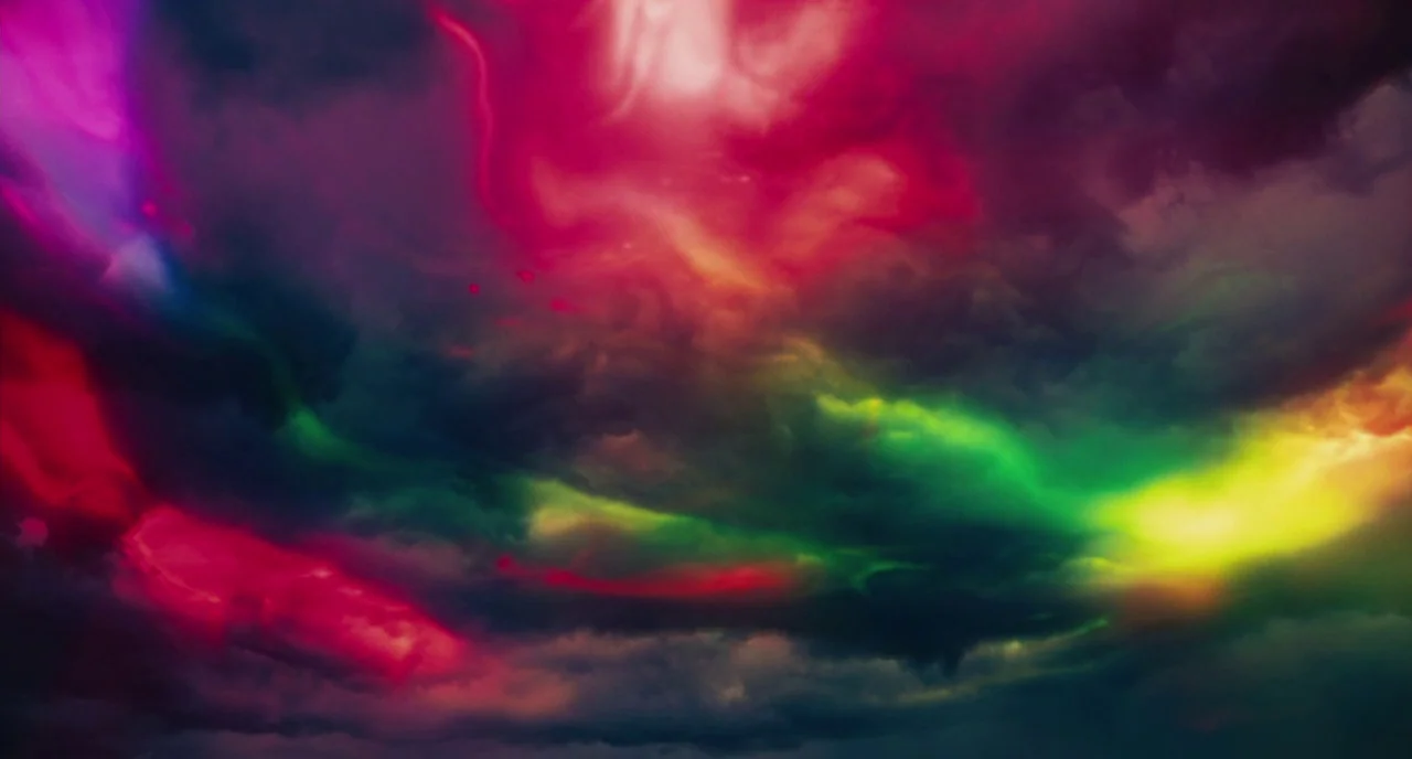 Fast Color (2018) movie still: establishing — A dense blanket of dark, overcast clouds covers the entire frame. Vibrant streaks of magenta, green,…