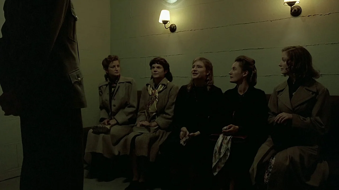 Downfall (2004) movie still: medium — A austere waiting area with concrete block walls and two dim wall sconces overhead. Five women in 1940s-style…