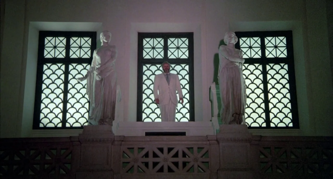The Belly of an Architect (1987) movie still: fullbody — A grand interior space features three symmetrical windows behind a stone-balustrade…