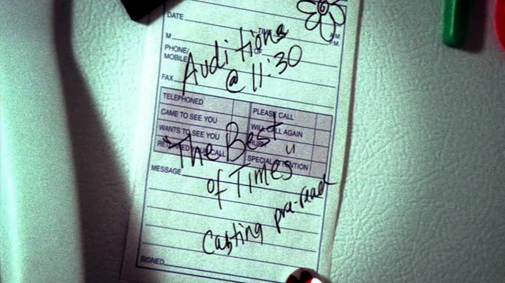 Smiley Face (2007) movie still: closeup — A white paper telephone memo is stuck to a textured refrigerator door surface. Handwritten ink notes on…
