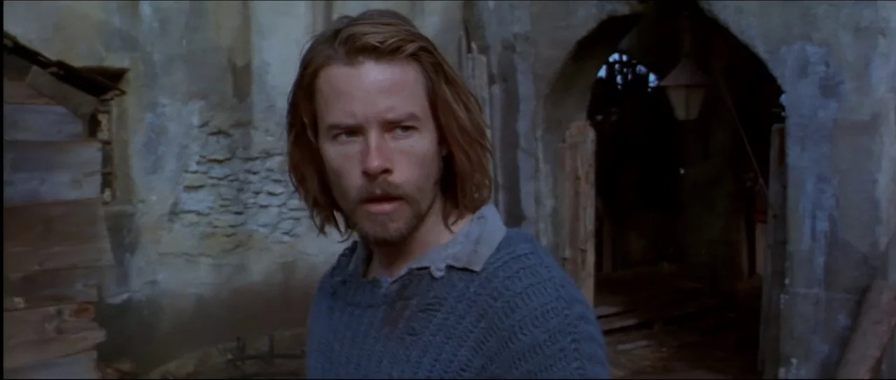 Ravenous (1999) movie still: medium — A dilapidated structure featuring weathered stone walls and an arched stone doorway. A man stands in the…