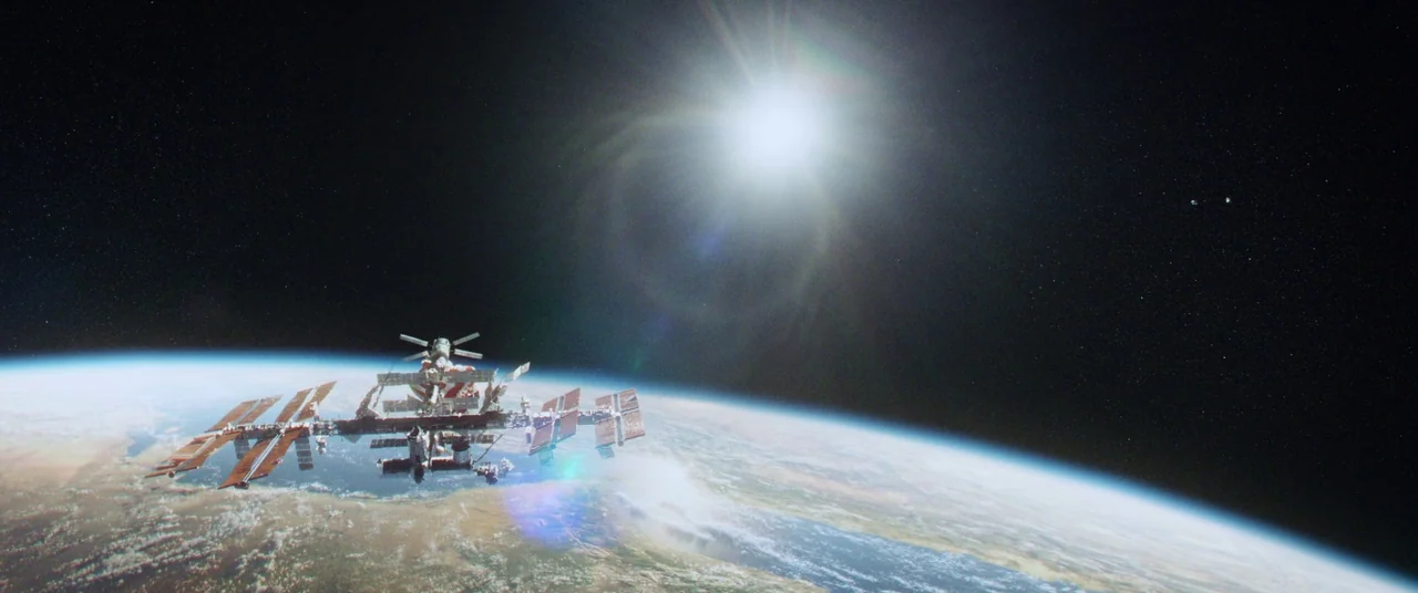 Gravity (2013) movie still: establishing — An international space station floats in orbit high above the curved horizon of Earth. The sun shines…