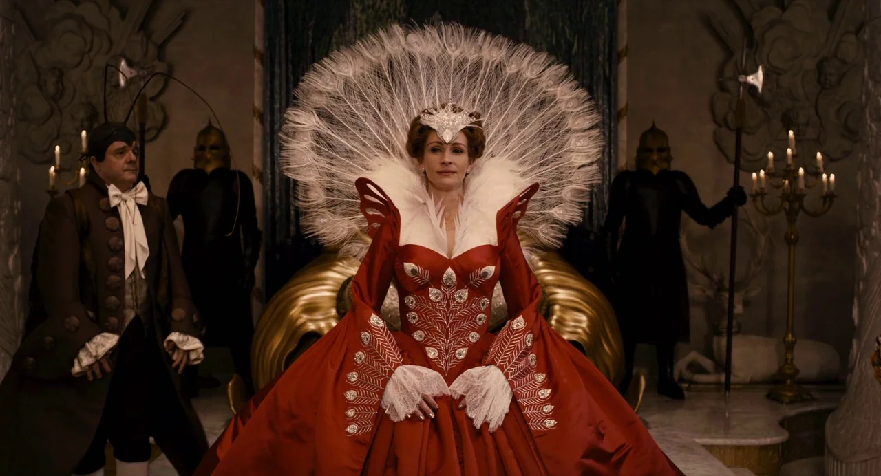 Mirror Mirror (2012) movie still: medium — A stone throne room features ornate carvings and statues in the background. A woman sits on a golden…