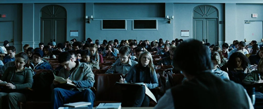 Wind Chill (2007) movie still: wide — A crowded university lecture hall features rows of students sitting in dark orange theater seats. Most…