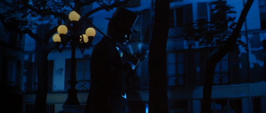 Gigi (1958) movie still: medium — A European city street at night features multi-globed streetlamps and residential buildings with shuttered…