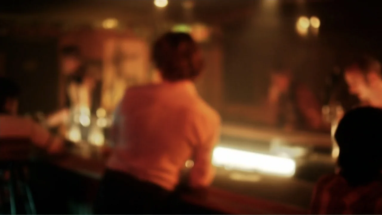 Behind the Candelabra (2013) movie still: medium — A dimly lit bar features a counter highlighted by a singular bright practical light. An…