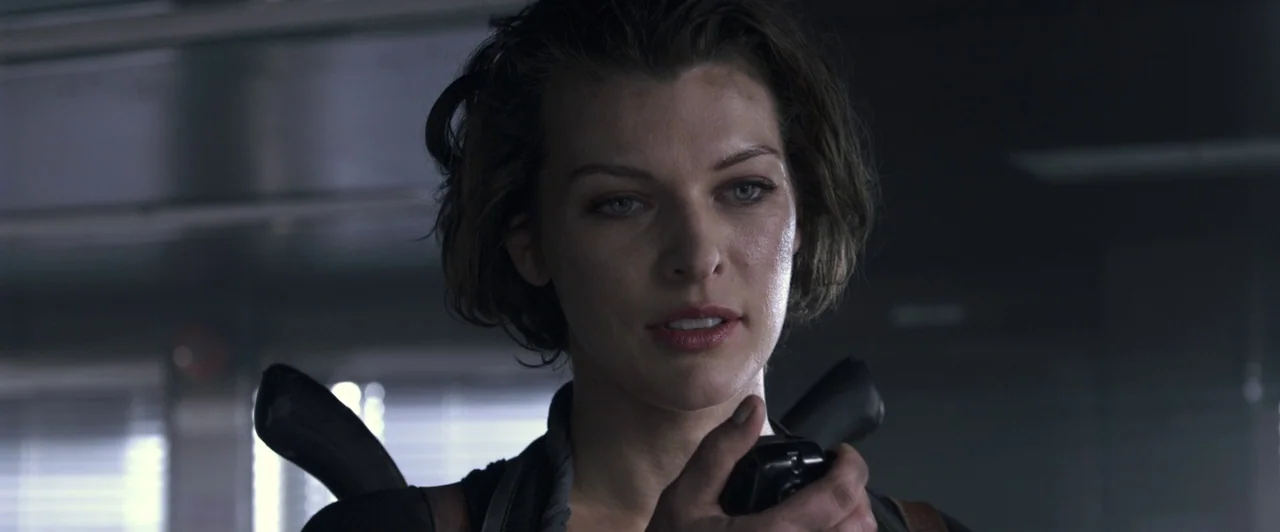 Resident Evil: Afterlife (2010) movie still: closeup — An industrial facility interior with metallic surfaces and dim fluorescent background…