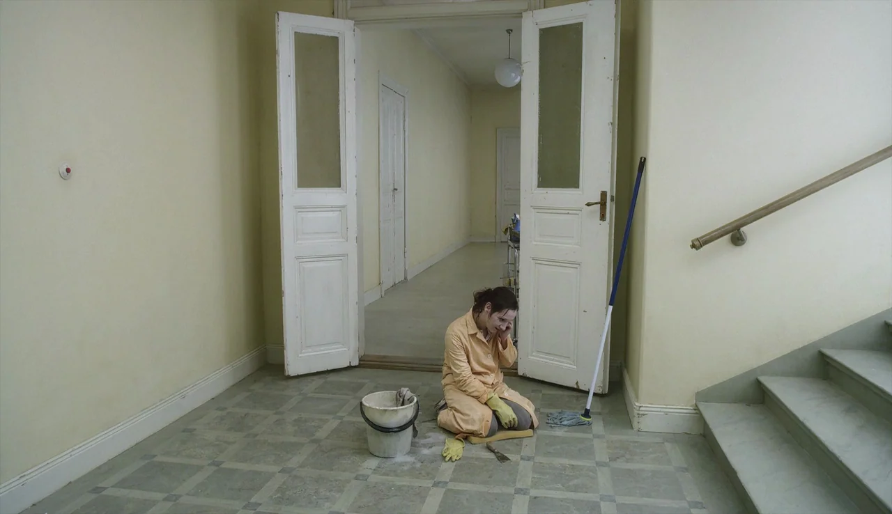 A Pigeon Sat on a Branch Reflecting on Existence (2014) movie still: wide — A quiet tiled landing features double doors and a staircase leading…