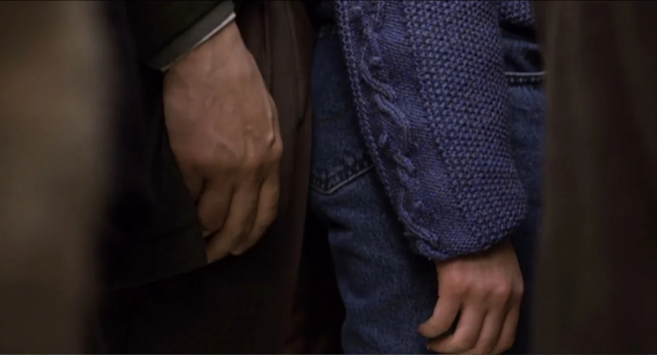 The Holy Girl (2004) movie still: closeup — Two individuals stand in close proximity in an unidentifiable, dimly lit public environment. A person in…