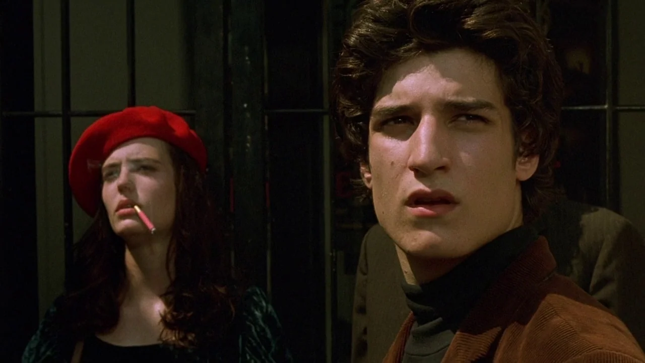 The Dreamers (2003) movie still: medium — A dark metal gate stands in the background behind two young people outdoors. The man in the foreground…
