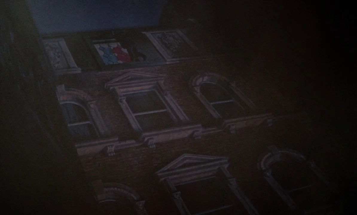Dr Jekyll & Sister Hyde (1971) movie still: establishing — A dark brick building facade with multiple arched windows rises against the night sky.…