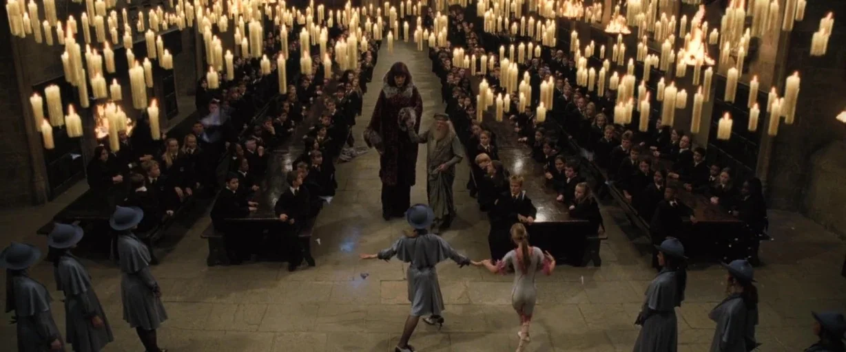 Harry Potter and the Goblet of Fire (2005) movie still: wide — A massive stone hall features long wooden tables filled with students under floating…