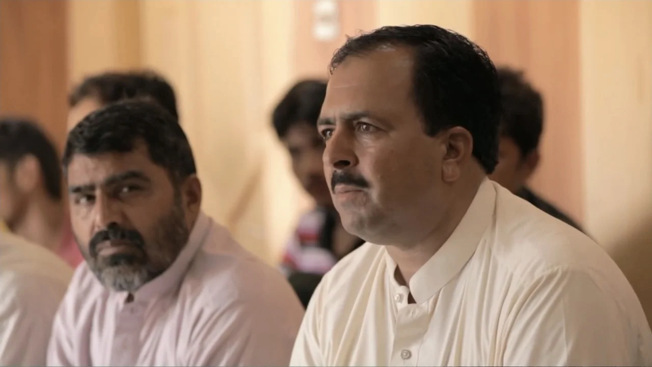 A Girl in the River: The Price of Forgiveness (2015) movie still: medium — An interior space features several men seated in rows attending a…