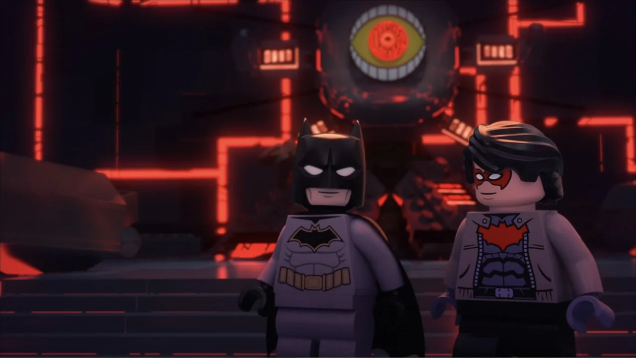 LEGO DC Batman: Family Matters (2019) movie still: medium — A dark tech-filled room features a glowing mechanical eye on the rear wall. Two lego…