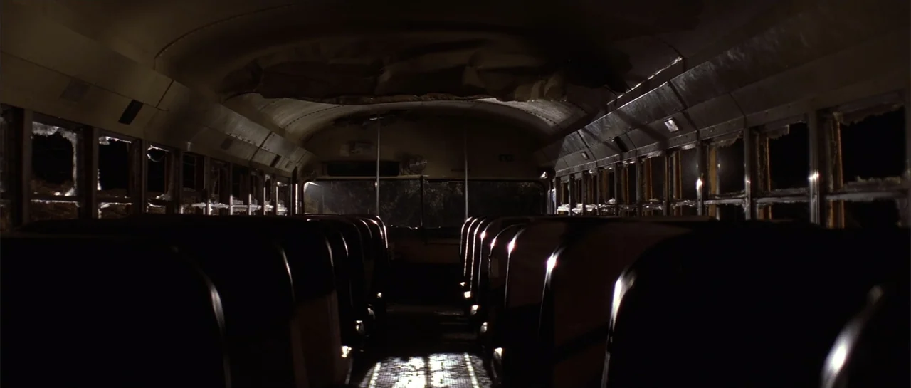 Jeepers Creepers 2 (2003) movie still: wide — The interior of a darkened bus features rows of empty seats facing forward. Many of the side windows…
