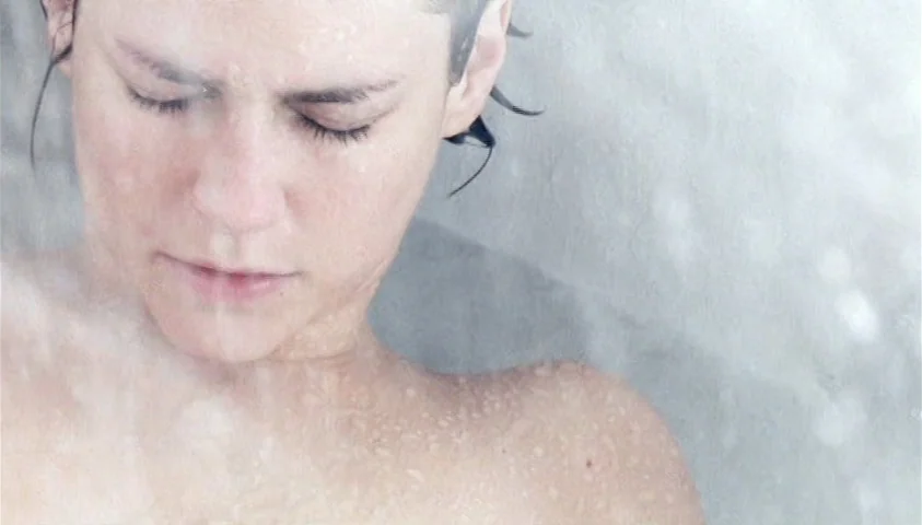 Maelström (2000) movie still: closeup — A person stands in a shower stall enveloped by a thick mist of water. The subject has eyes closed and face…