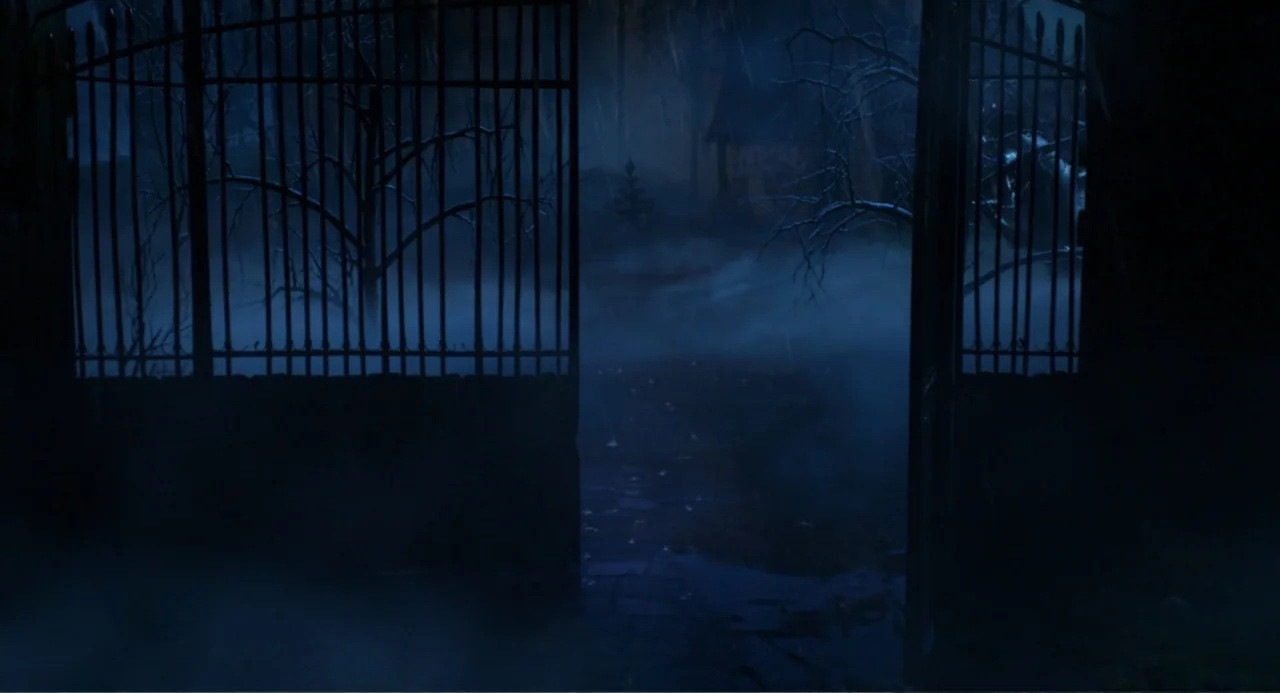 Hotel Transylvania: Transformania (2022) movie still: establishing — A wrought iron gate stands open to a dark, fog-filled yard at night. Bare trees…