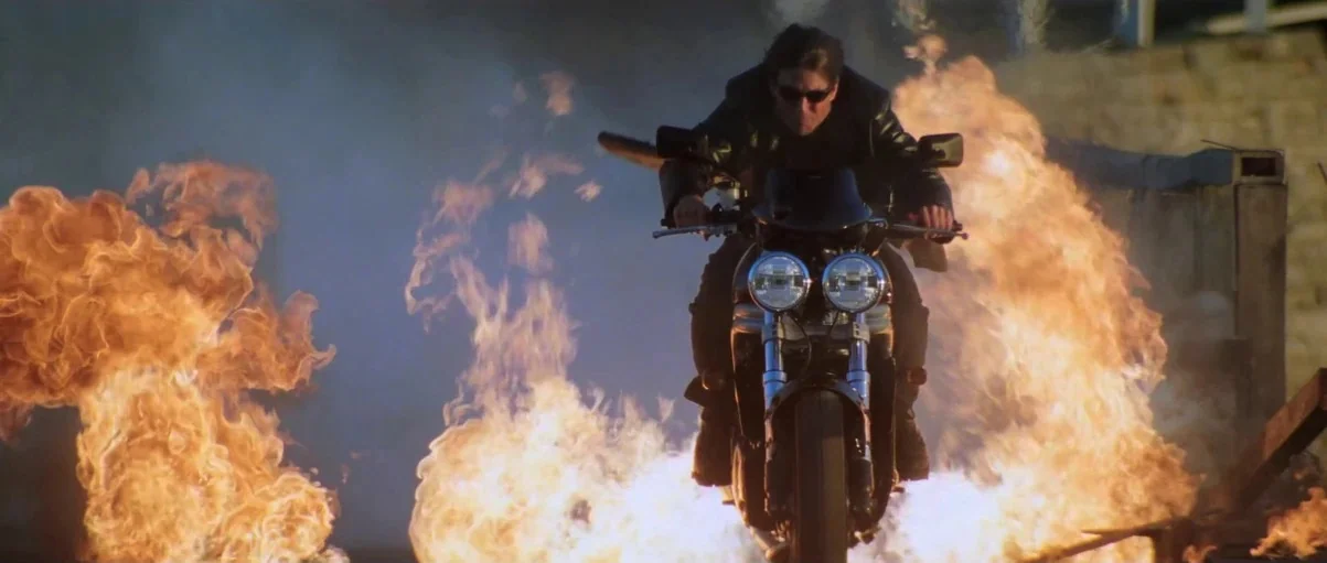 Mission: Impossible – Ghost Protocol (2011) movie still: medium — A man rides a motorcycle through a series of large, bright orange explosions. The…