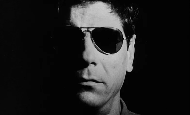 La Jetée (1962) movie still: closeup — A man's face emerges from complete darkness in a stark, high-contrast black-and-white composition. The…