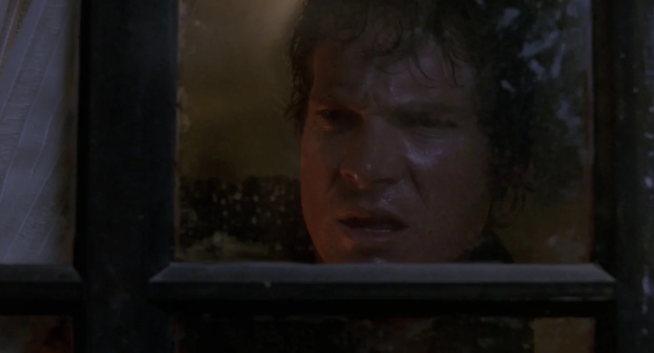 House of Wax (2005) movie still: closeup — A dark night exterior features a man looking through a glass window pane. The man has a tense expression…