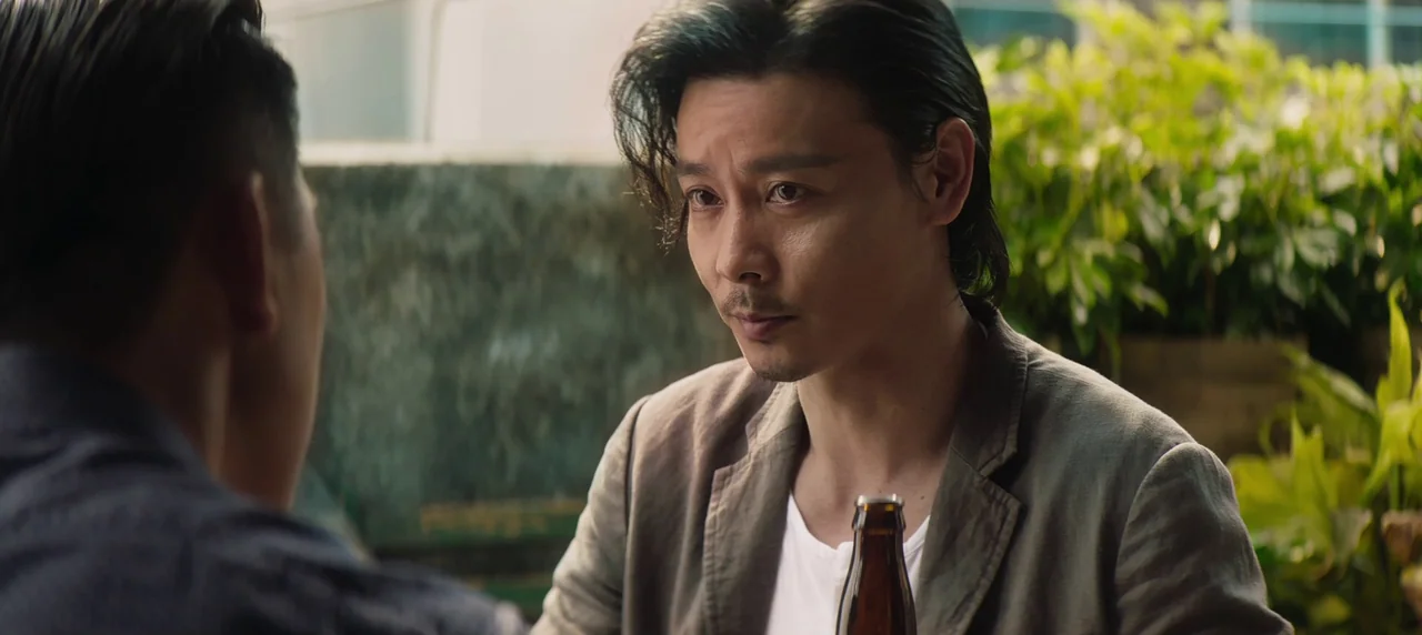 Master Z: The Ip Man Legacy (2018) movie still: medium — A restaurant setting with green plants in the background and a brown beer bottle. Two men…